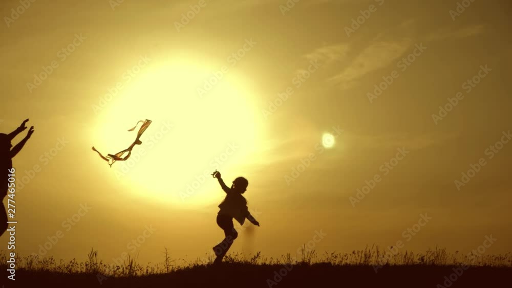Happy family playing with a kite while on meadow, sunset, in summer day. Funny family time. Happy little girl launch a kite with parents. Mom, Dad and daughter are happy together. Happy family playing with a kite while on meadow, sunset, in summer day. Funny family time. Happy little girl launch a kite with parents. Mom, Dad and daughter are happy together.