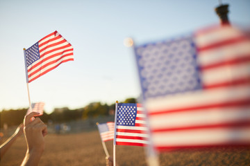 Crowd of unrecognizable people holding US stick flags while preserving memory of American heroes