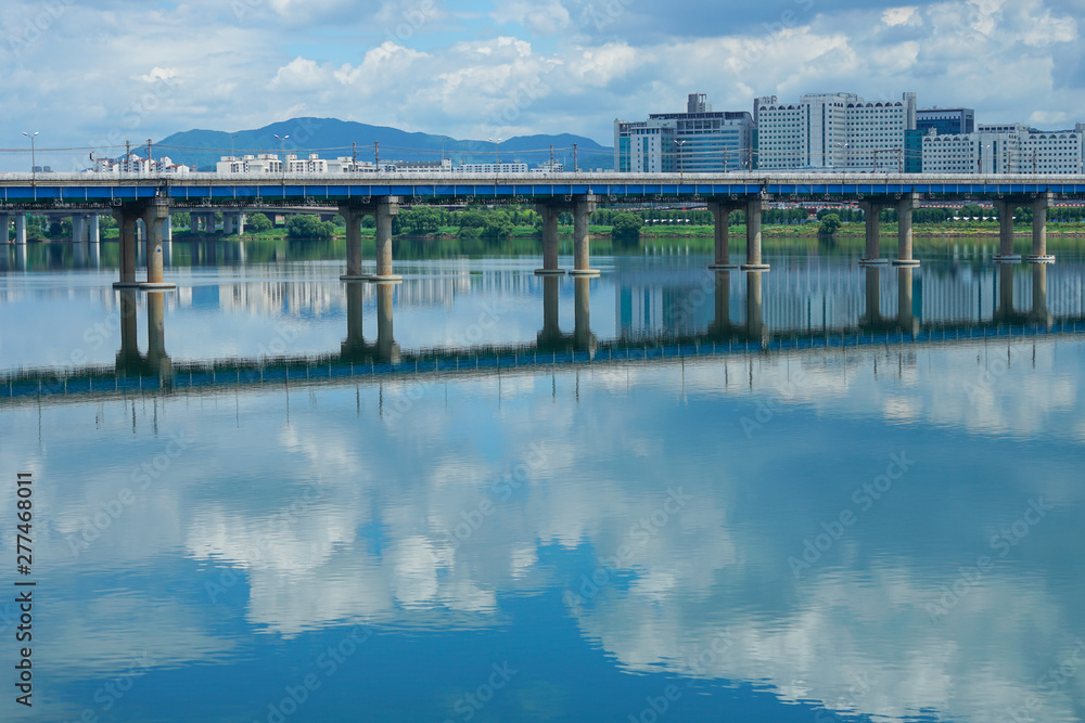 View of Jamsil  Bridge over the Han River at downtown of Seoul in South Korea. cloud and blue sky reflected in water. Beautiful cityscape.