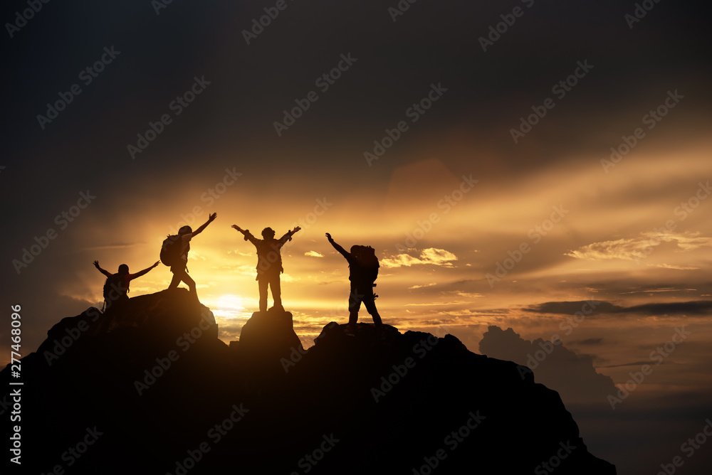 Silhouette of Hikers climbing up mountain cliff. Climbing group helping each other while climbing up in sunset. Concept of help and teamwork, Limits of life and Hiking success full.