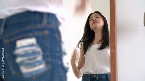 Young beautiful asian woman look at mirror after wear clothes her checking body for ready next travel trip on summer in hotel room. photo