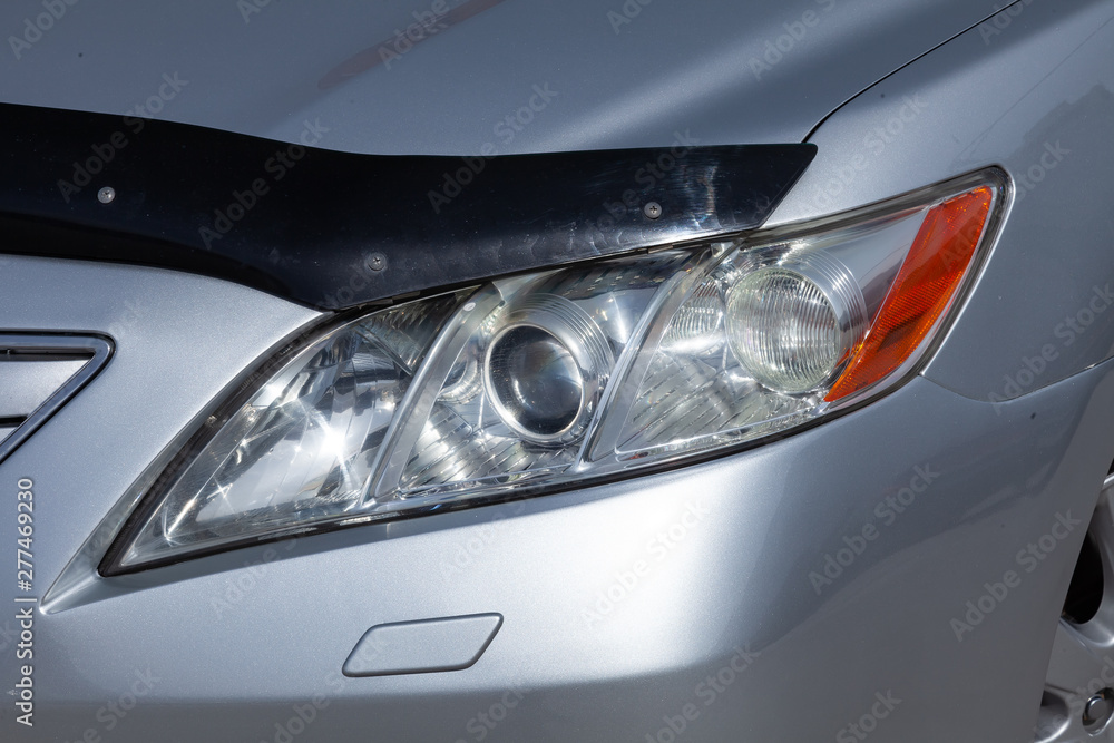 Front Headlight of car in silver color after cleaning before sale in a sunny day on parking