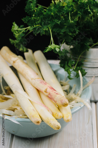 Bunch of raw uncooked white asparagus over rustic white wooden tray background. Seasonal harvest product. Local market food concept.  Top view, close-up