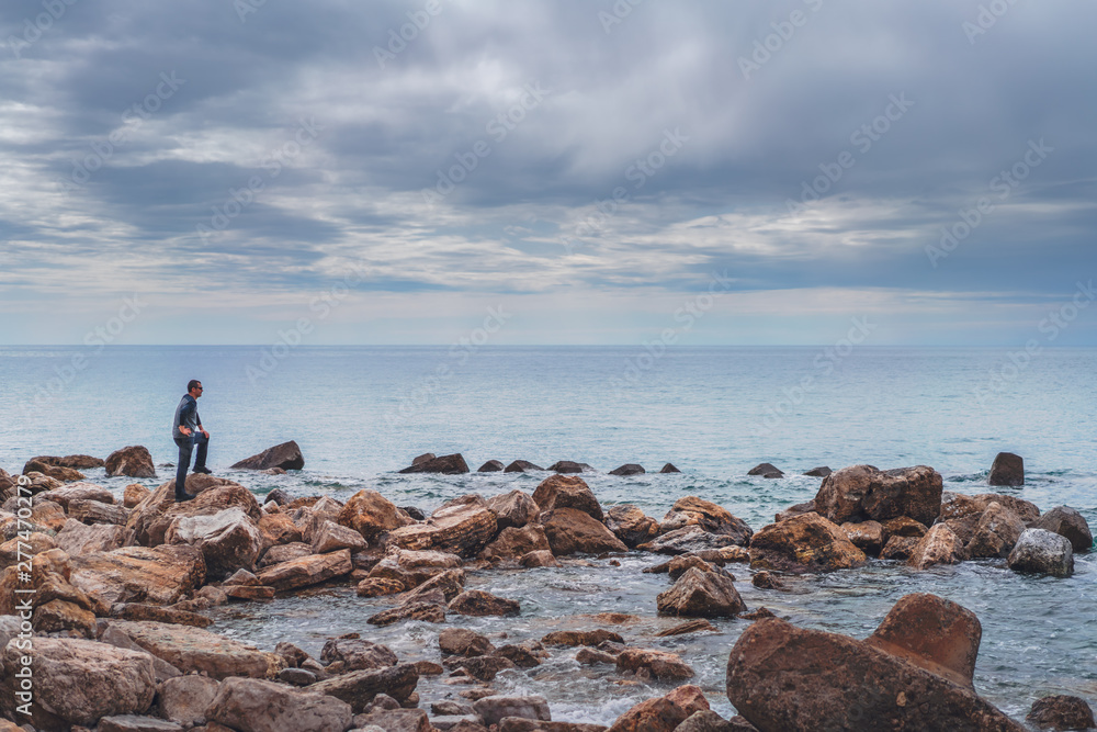 Man looking at the sea on a rocky coast