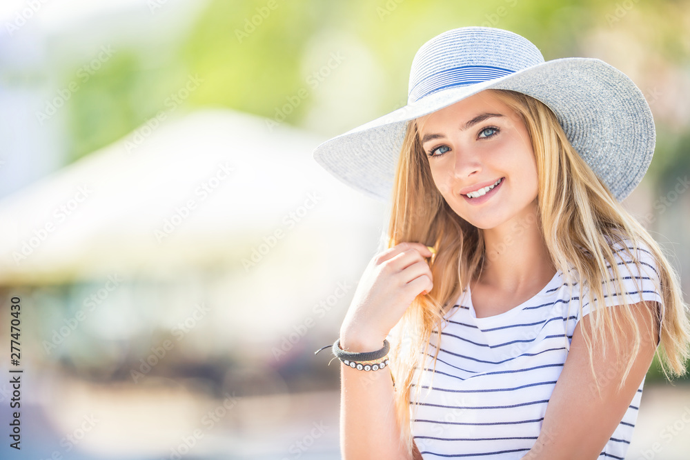 Summer portrait of young beautiful woman in hat sitting on bench in park - obrazy, fototapety, plakaty 