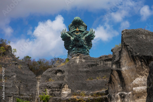 impressive view of Garuda Wisnu green copper statue inspired in Hindu myth standing majestic under a blue sky in Indonesia travel destination landmark © TheVisualsYouNeed