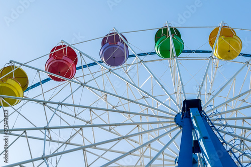 ferris wheel from the amusement Park with colorful baskets of seats against the blue sky