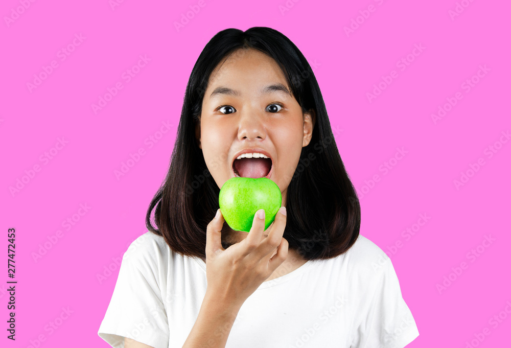 A young girl holding a green apple with the pink background A young girl holding a green apple with the pink background