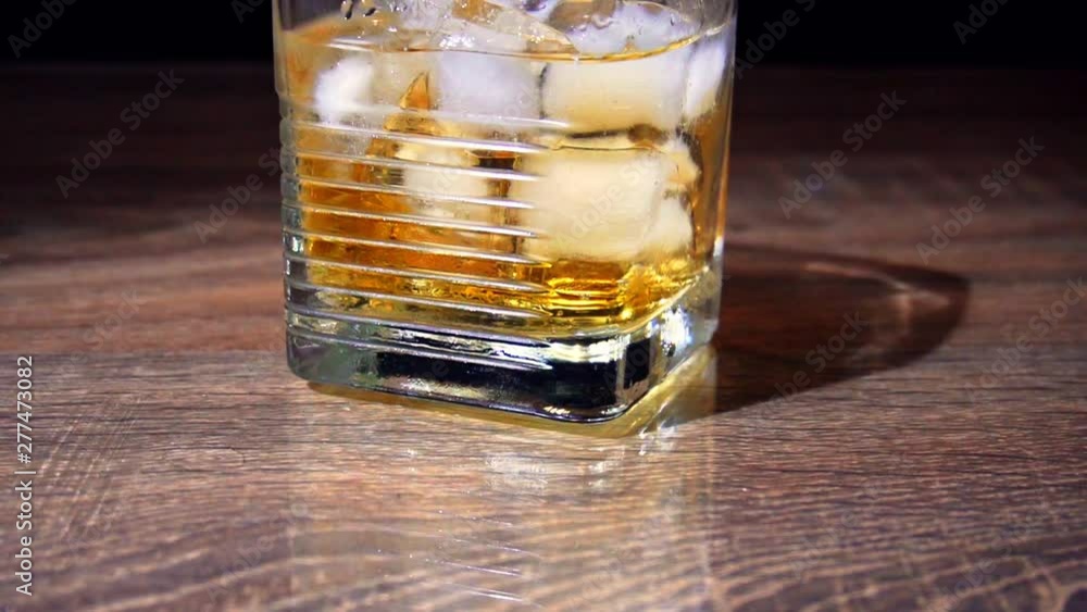 Glass with ice and scotch whiskey on a wooden table. Dark background Glass with ice and scotch whiskey on a wooden table. Dark background