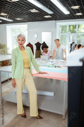Beautiful elderly fashion designer standing in a workshop