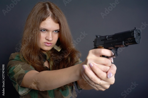 Beautiful elegant girl aims at gun