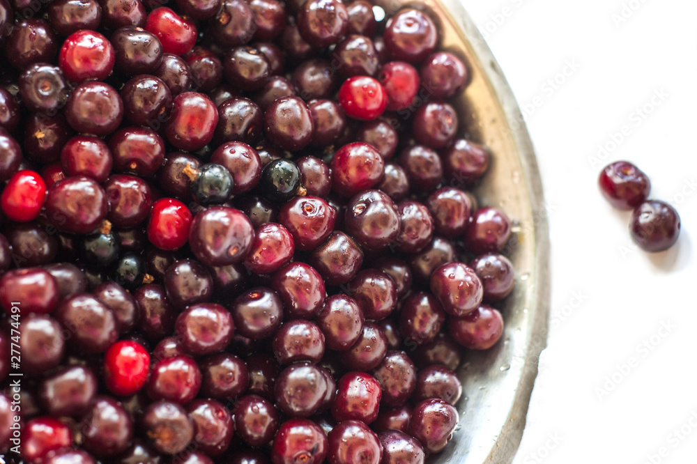 Fresh cherry with water drops in an iron bowl on a white background Fresh cherry with water drops in an iron bowl on a white background