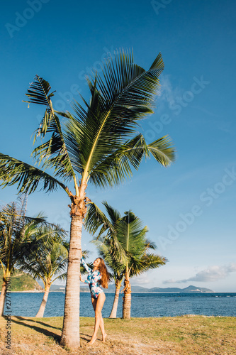 Fototapeta Naklejka Na Ścianę i Meble -  beautiful girl near palm trees in front of the sea in Sanya
