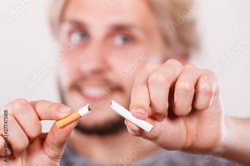 Smilling man is breaking a cigarette