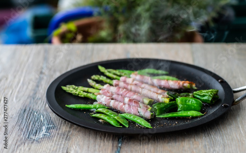 Fried asparagus wizh bacon and vegetables in a pan . photo