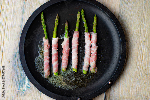 Fried asparagus wizh bacon and vegetables in a pan . photo