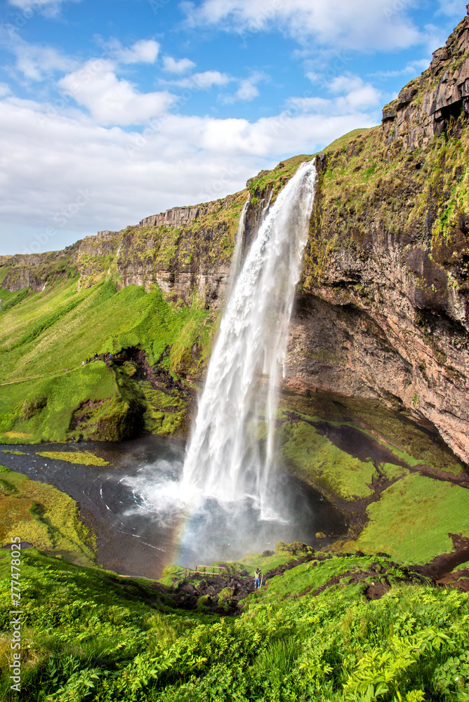 Fototapeta premium Uroczy, piękny wodospad Seljalandsfoss na Islandii z tęczą. Kraje egzotyczne. Niesamowite miejsca. Popularna atrakcja turystyczna.
