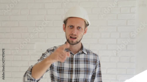Angry male engineer in hardhat pointing at you and reprehending