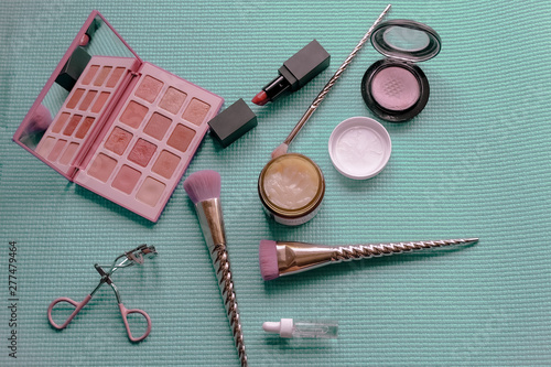 Brush and cosmetic isolated on a green pastel background. Top view.