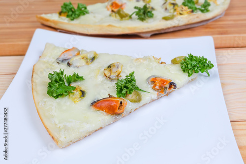 Slice of cooked pizza with mussels on the square dish