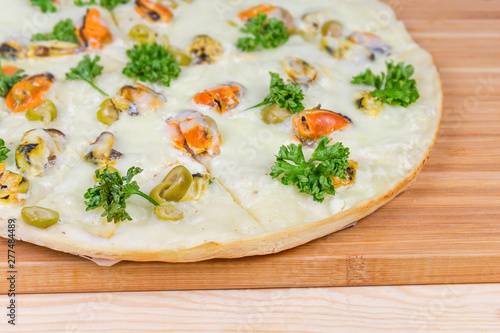 Part of cooked pizza with mussels on cutting board closeup