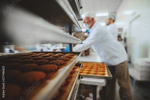 Two hard working food plant employees in sterile uniforms packing cookies in boxes.