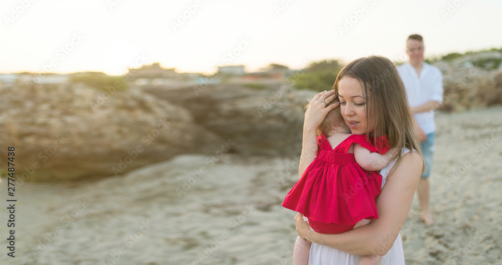 Young parents with cute baby girl outdoors on the beach, happy family concept, free space for your text Young parents with cute baby girl outdoors on the beach, happy family concept, free space for your text