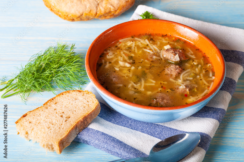 Homemade soup with noodles and meatballs on a wooden table. Traditional rural dinner Homemade soup with noodles and meatballs on a wooden table. Traditional rural dinner