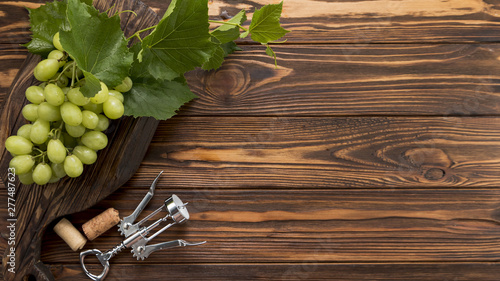 Obraz na plátně Bunch of grapes with corkscrew on wooden background