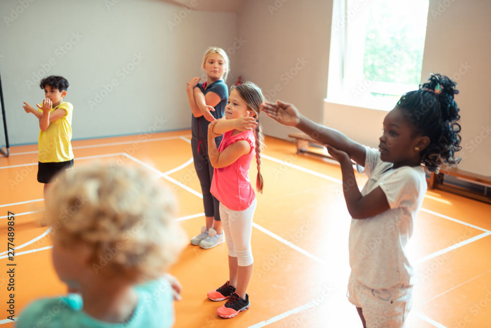 Elementary school children working out at sports lesson. - obrazy, fototapety, plakaty 