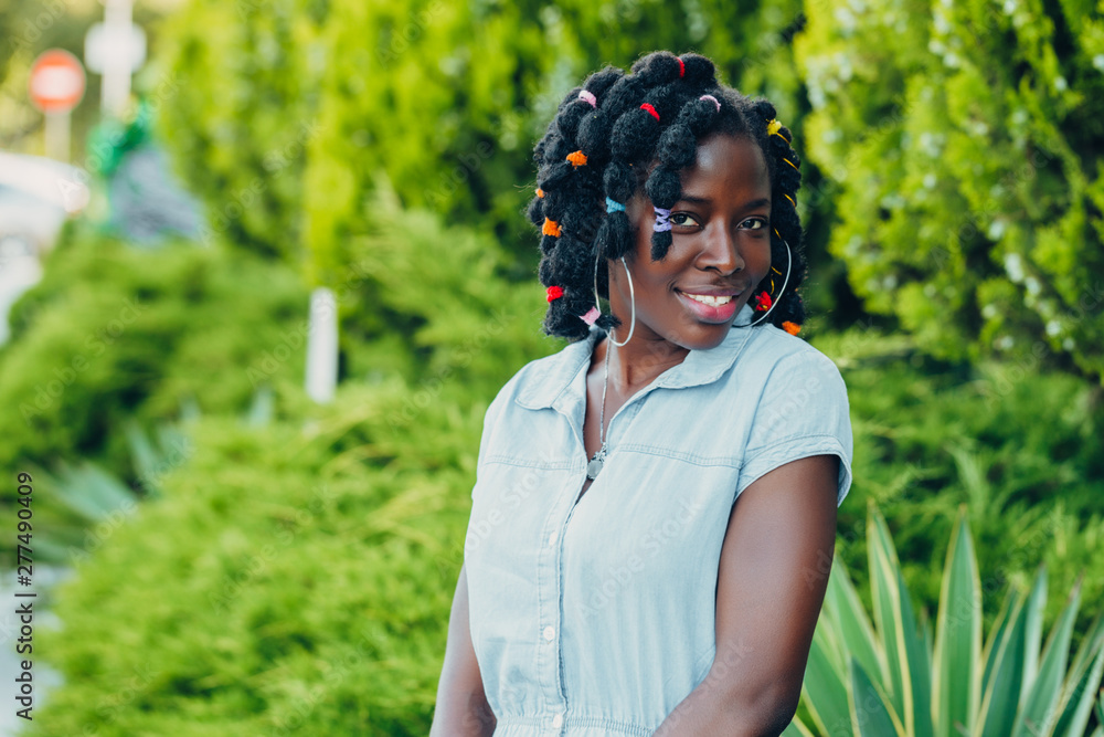 Portrait of a African beauty smiling young black woman in a park with sunlight flare and copy space Portrait of a African beauty smiling young black woman in a park with sunlight flare and copy space