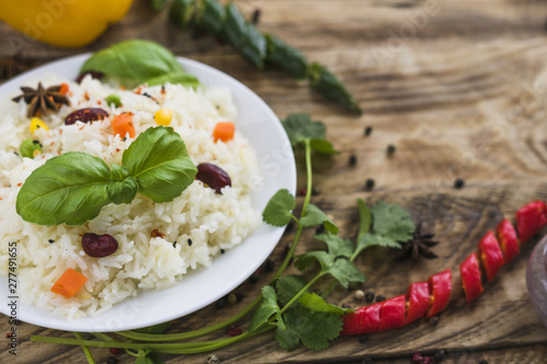 Close-up of healthy rice; basil leaves; on plate with parsley and chili peppers on blurred background
