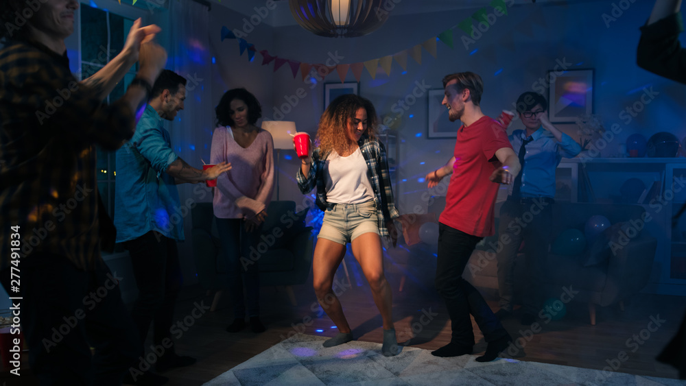 At the College House Party: Sexy Couple Dances with Diverse Group of Friends Having Fun Around Them. Boys and Girls Clubbing in the Living Room. Disco Neon Strobe Lights Illuminating Room. At the College House Party: Sexy Couple Dances with Diverse Group of Friends Having Fun Around Them. Boys and Girls Clubbing in the Living Room. Disco Neon Strobe Lights Illuminating Room.