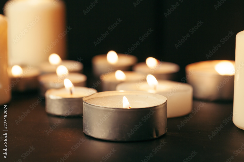 Many candles burning at night. Many candle flames glowing on dark background Many candles burning at night. Many candle flames glowing on dark background