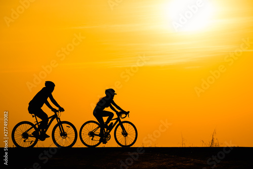 Silhouette woman cycling on sunset background