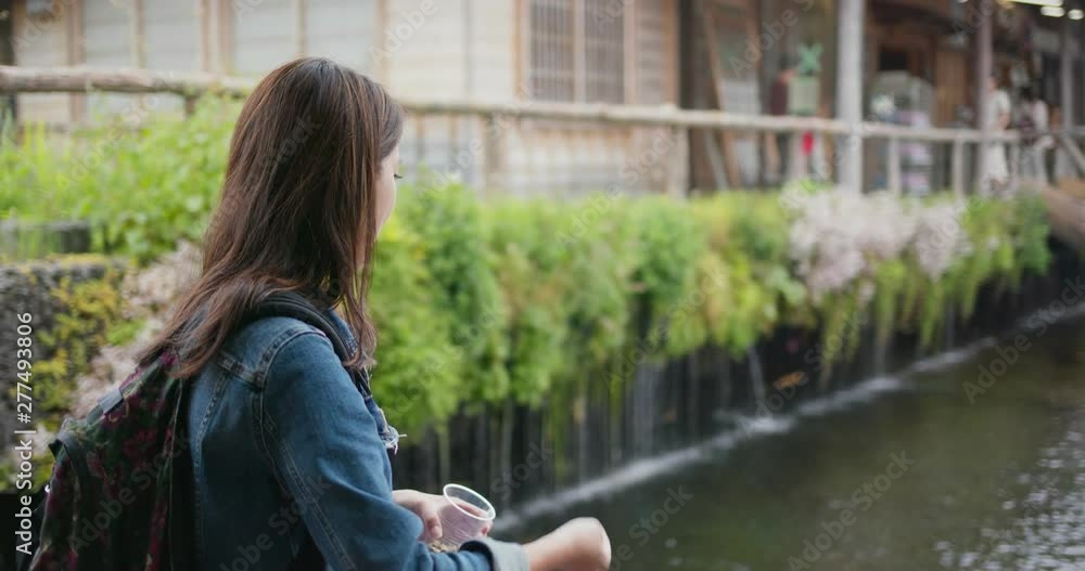 Woman feed koi fish in Japanese garden
