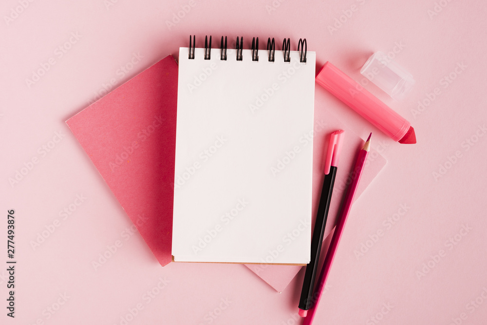 Pink composition with notepad and office supplies on colored surface - obrazy, fototapety, plakaty 