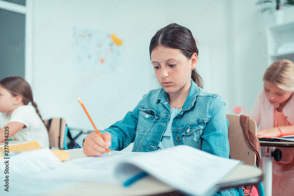 School girl looking anxiously at her maths test. School girl looking anxiously at her maths test.