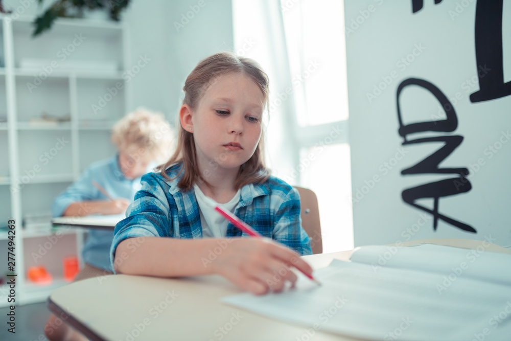 Tired school girl writing her maths test. Tired school girl writing her maths test.