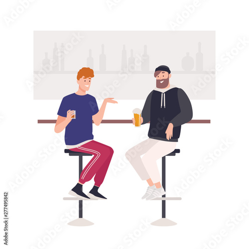 Pair of happy friends sitting on stools at bar counter and drinking beer or a...