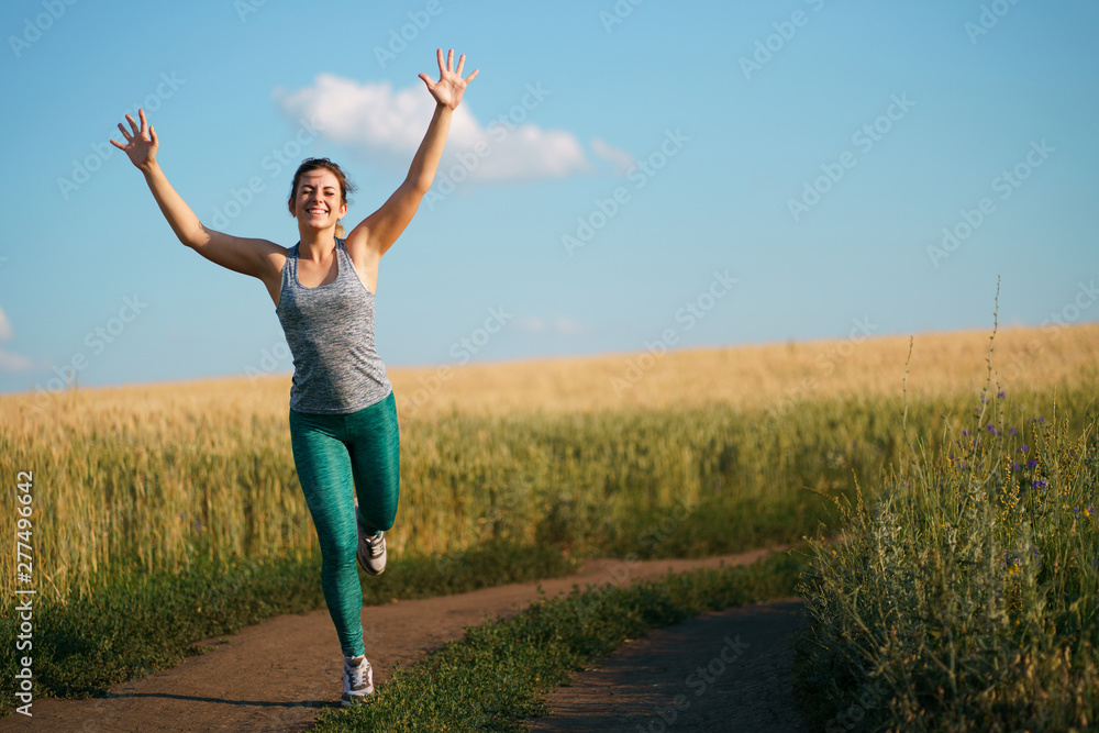 Happy woman on sunset or sunrise. Female runner raising arms expressing positivity and success. Happy woman on sunset or sunrise. Female runner raising arms expressing positivity and success.