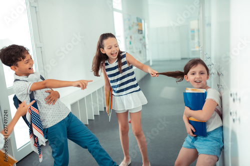 Rude violent children touching hair of girl while bullying her