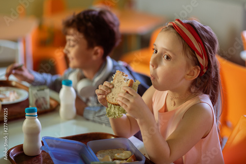 Quadro su tela Dark-haired schoolgirl chewing her sandwich while having lunch