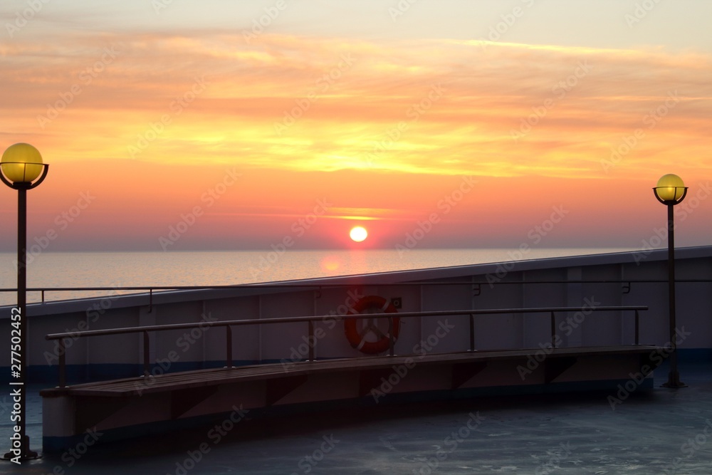 evocative image of a sunrise over the sea from a passenger ship with the sun rising over the horizon