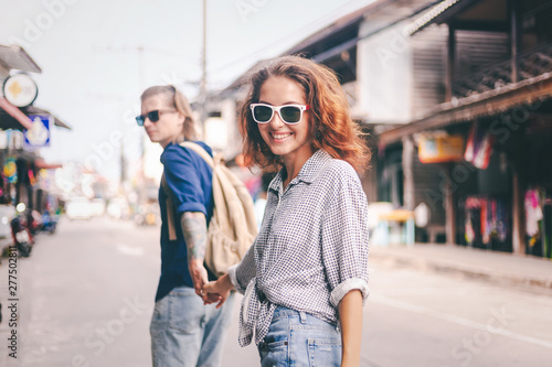 Young stylish beautiful couple travels Thailand man holding the hand of his happy girlfriend