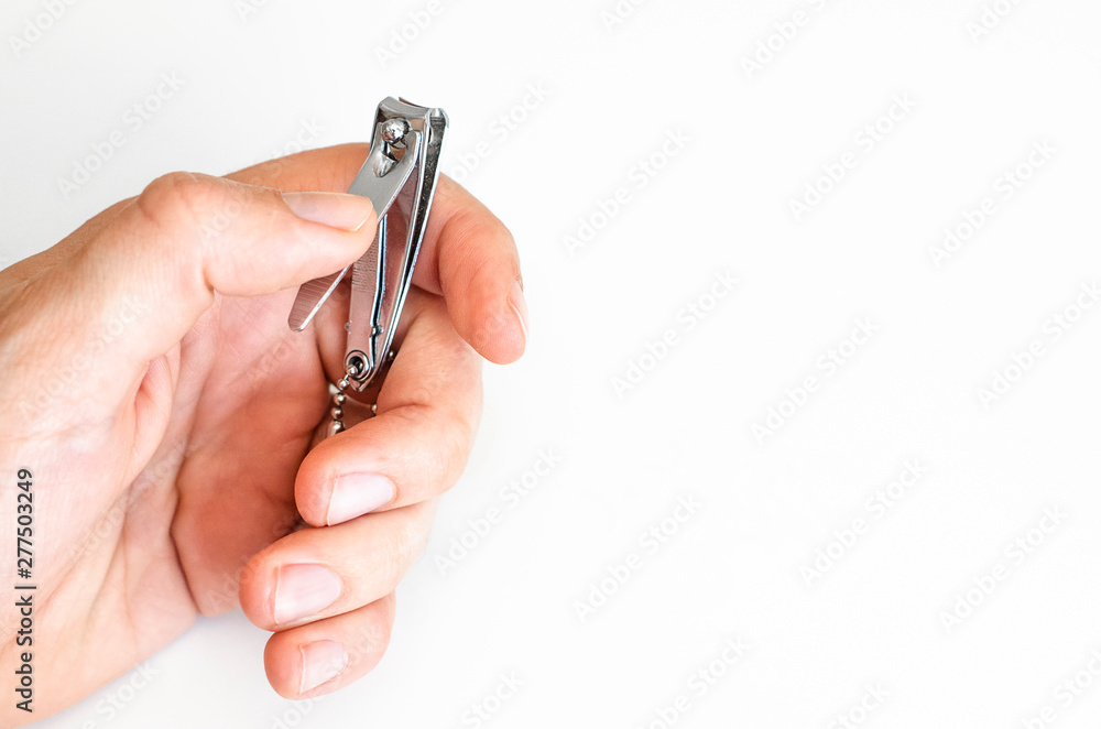 Young man holding a nail clipper tool. Young man holding a nail clipper tool.