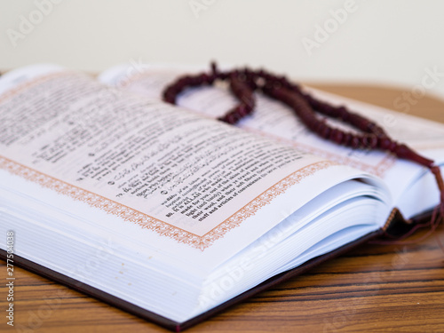 Islamic concept. Close up prayer from Quran book with rosary on a wooden background