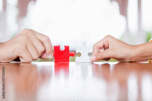 hands holding piece of red and white jigsaw puzzle. teamwork concept