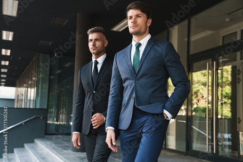 Portrait closeup of two concentrated businessmen partners walking together outside job center during working meeting photo