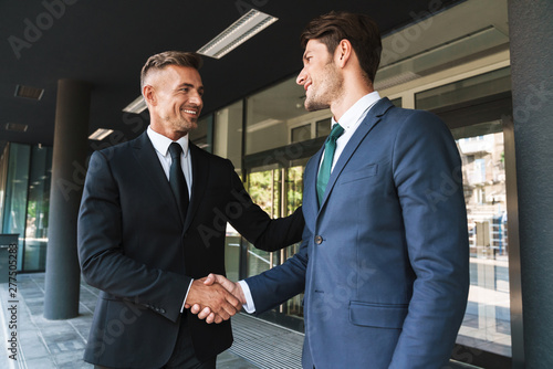 Portrait closeup of two successful businessmen partners shaking hands outside job center during working meeting